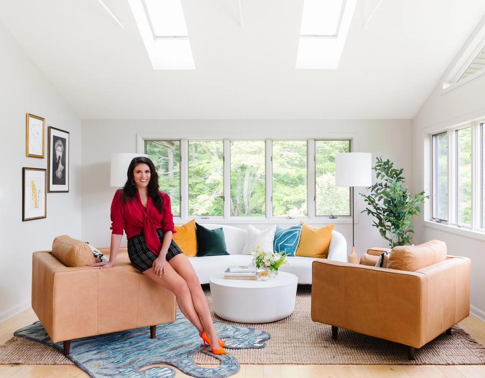 Bright modern living room with cognac leather chairs, colorful pillows, and natural light from large windows