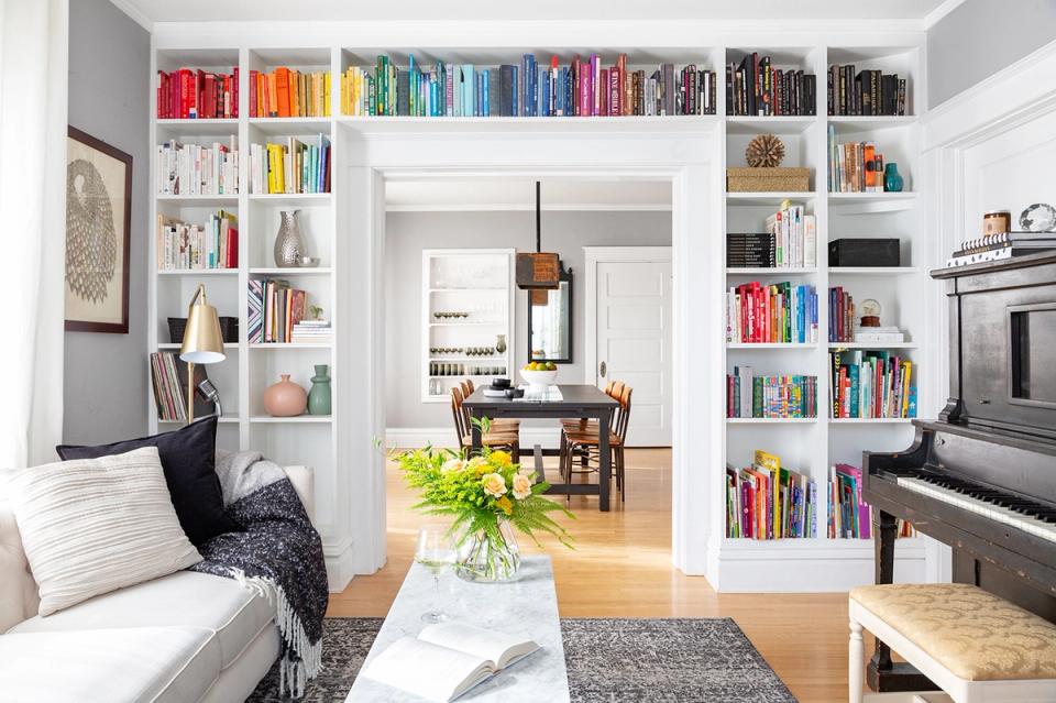 Scandinavian-inspired room with floor-to-ceiling white bookshelves, piano, and light-filled open layout