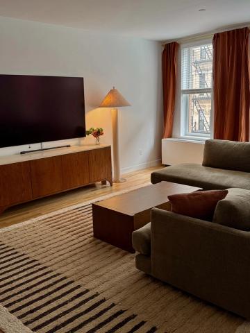 Warm mid-century modern living room with wood media console, warm lighting, burgundy curtains, and neutral tones