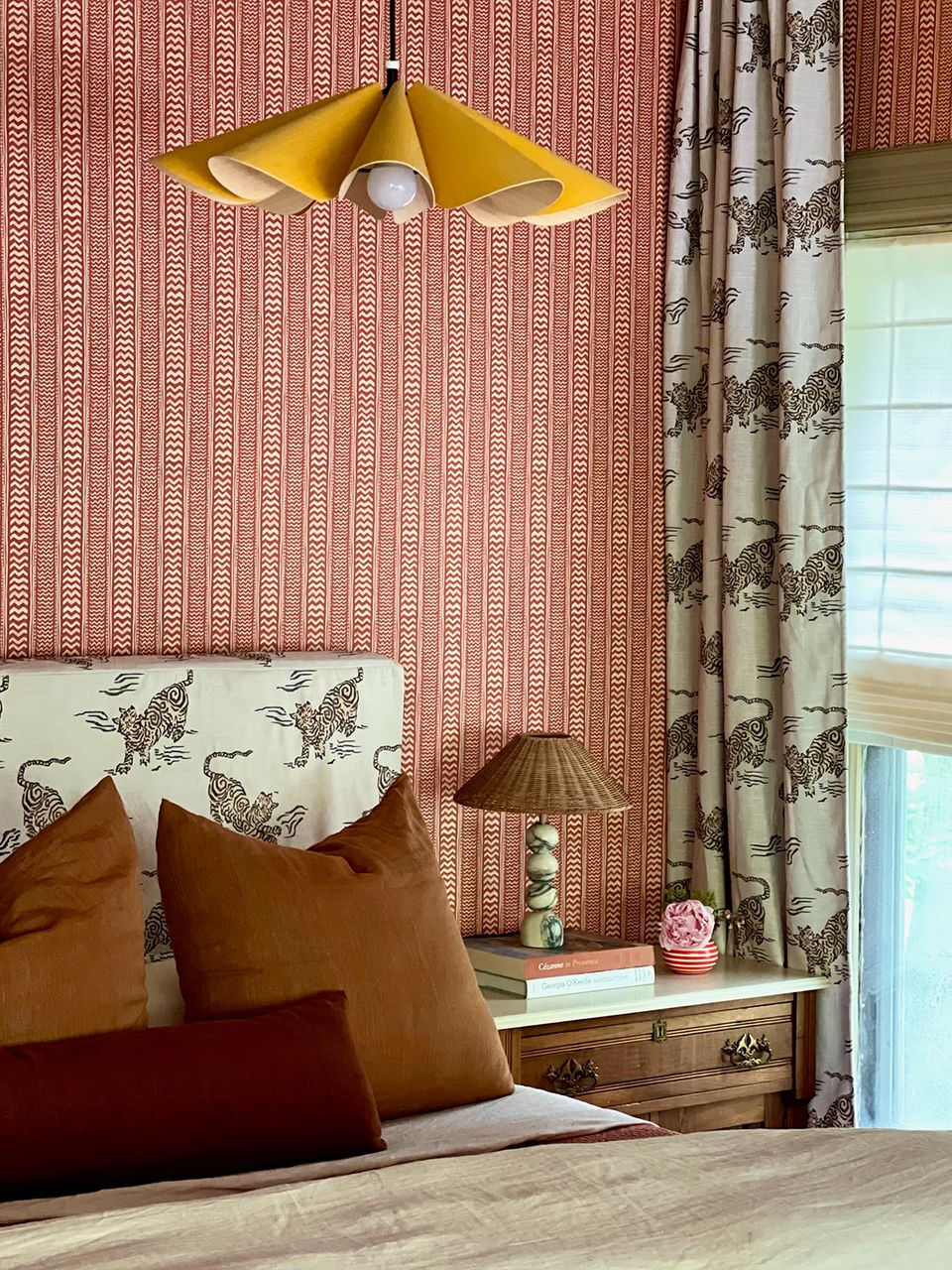 Eclectic bedroom mixing coral geometric wallpaper, botanical curtains, and mustard pendant