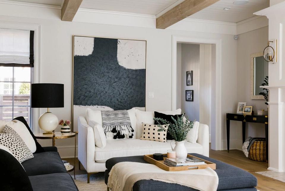 Modern living room with dark abstract wall art anchoring cream seating and warm wood accents