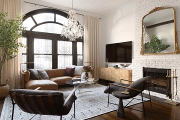 Transitional living room blending warm cognac leather, cream drapery, exposed brick, and an arched window for timeless elegance