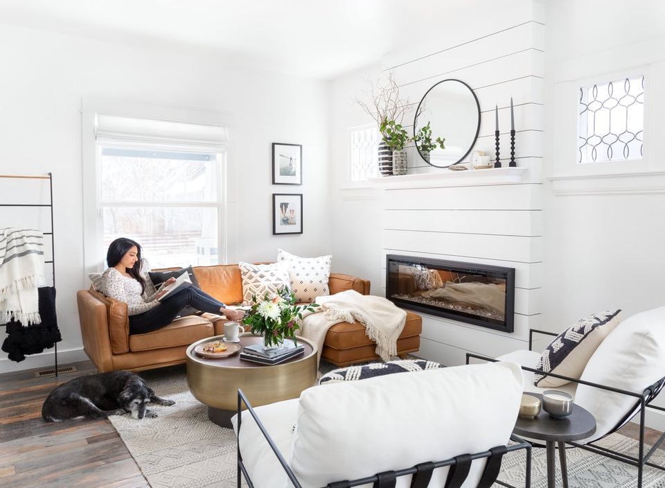 Bright Scandinavian living room with warm cognac leather sofa, white shiplap fireplace, and natural wood accents