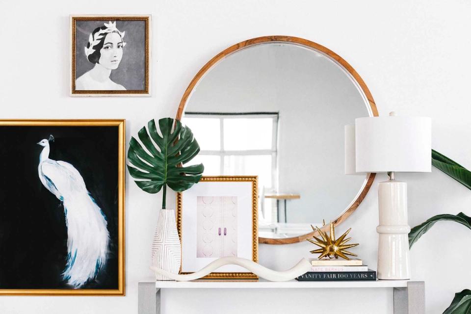 Modern entryway with botanical art, round wood mirror, white accents, and green plants