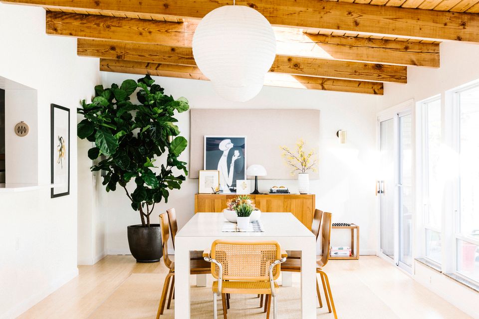 Light-filled mid-century dining space with exposed beams, natural wood furniture, and greenery