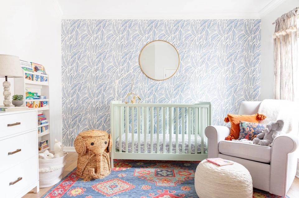Contemporary nursery with sage crib, patterned rug, textured accent wall, and layered seating