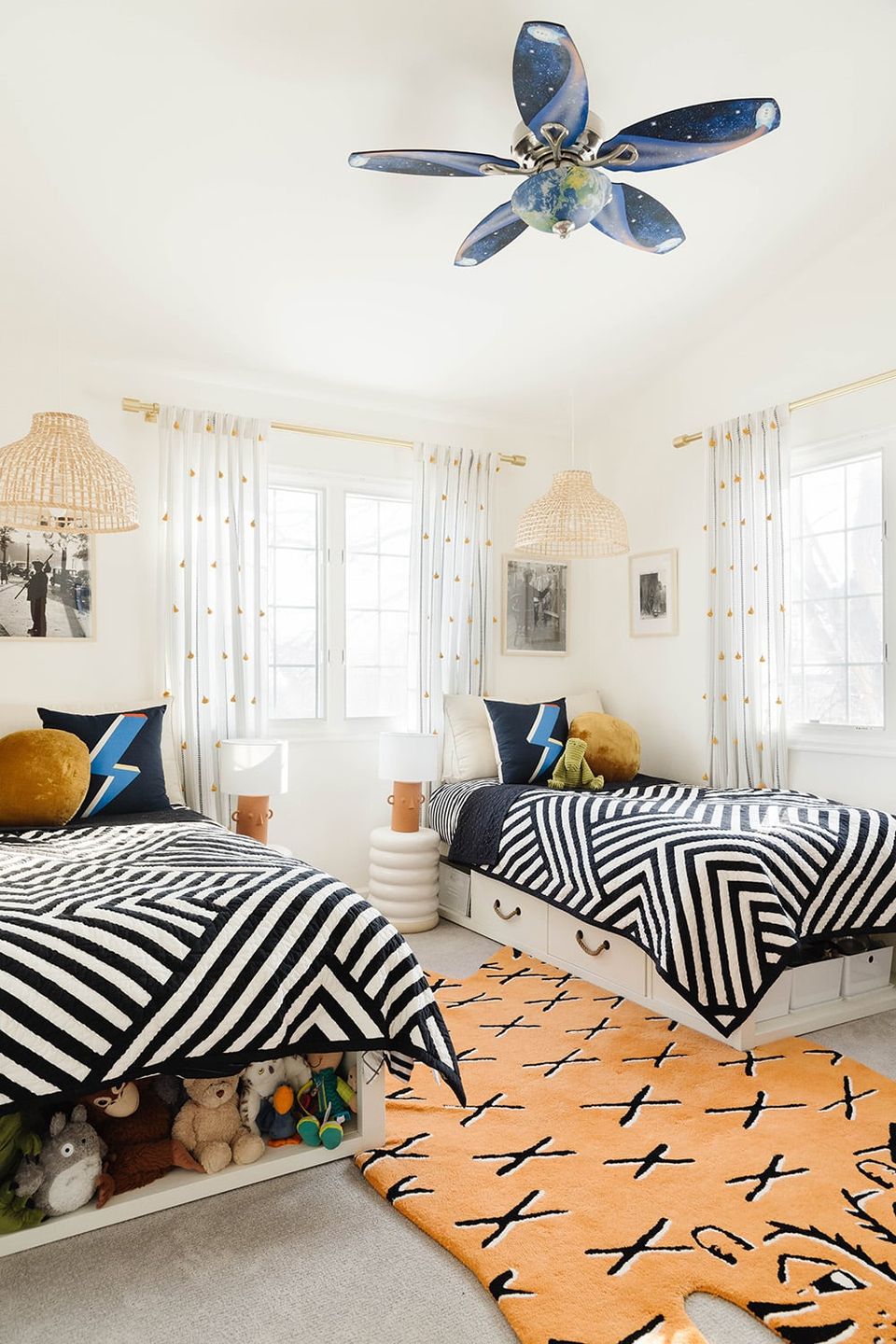 Modern boys bedroom with bold black and white geometric bedding, orange patterned rug, and light-filled space with minimalist coastal touches.