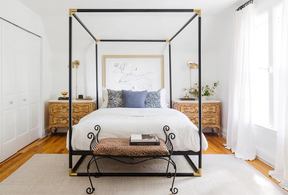 Eclectic bedroom blending brass, black, and natural wood with canopy bed frame