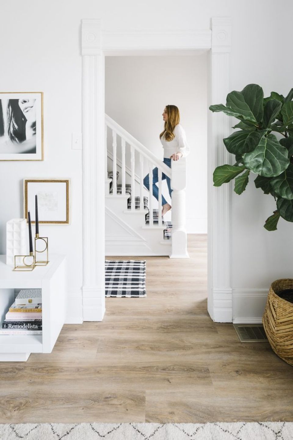 Scandinavian-inspired foyer with white shiplap, warm wood flooring, statement monstera plant, and curated wall gallery