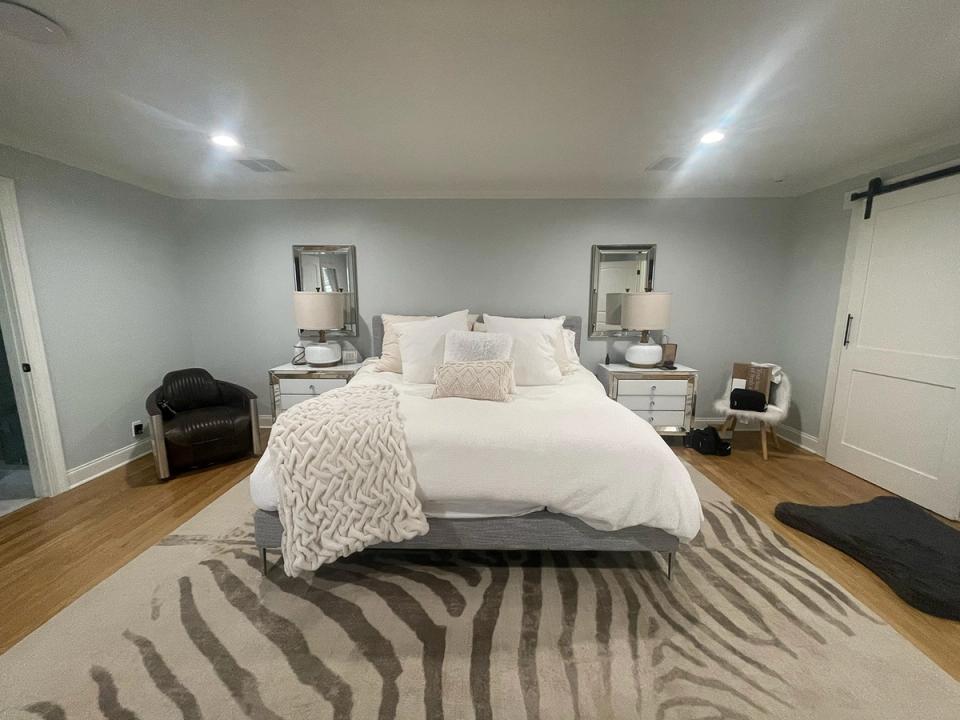 Serene neutral bedroom with soft cream tones, geometric striped rug, and minimalist styling