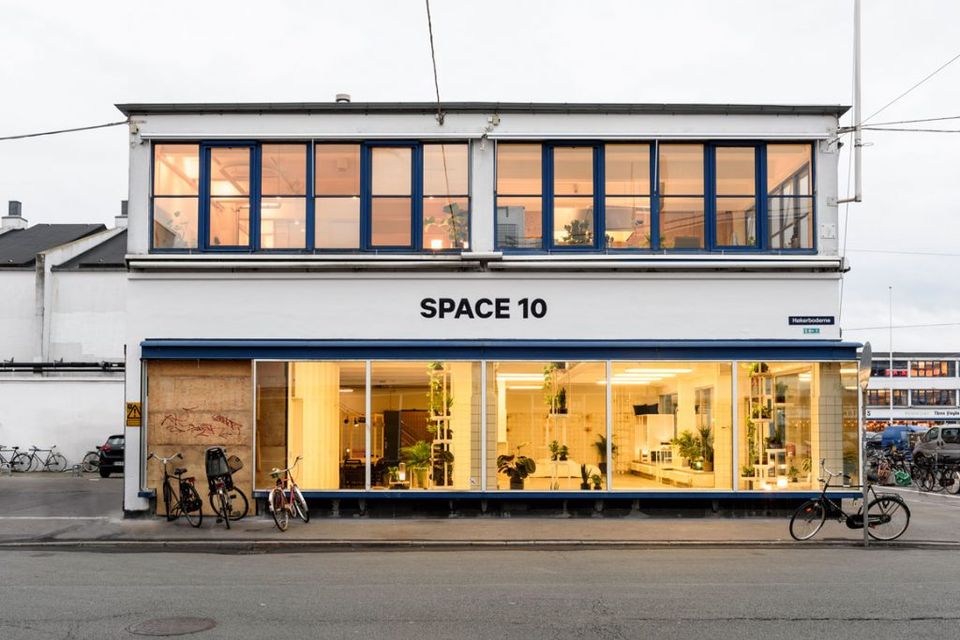 Modern industrial storefront with warm golden interior lighting, sleek black framing, minimalist contemporary design