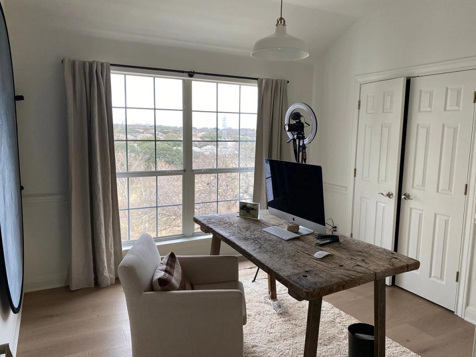 Bright industrial workspace with reclaimed wood desk, neutral palette, and expansive gridded windows