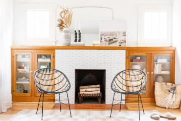 Mid-century modern fireplace nook with warm wood cabinetry, geometric woven chairs, and painted white subway tile surround