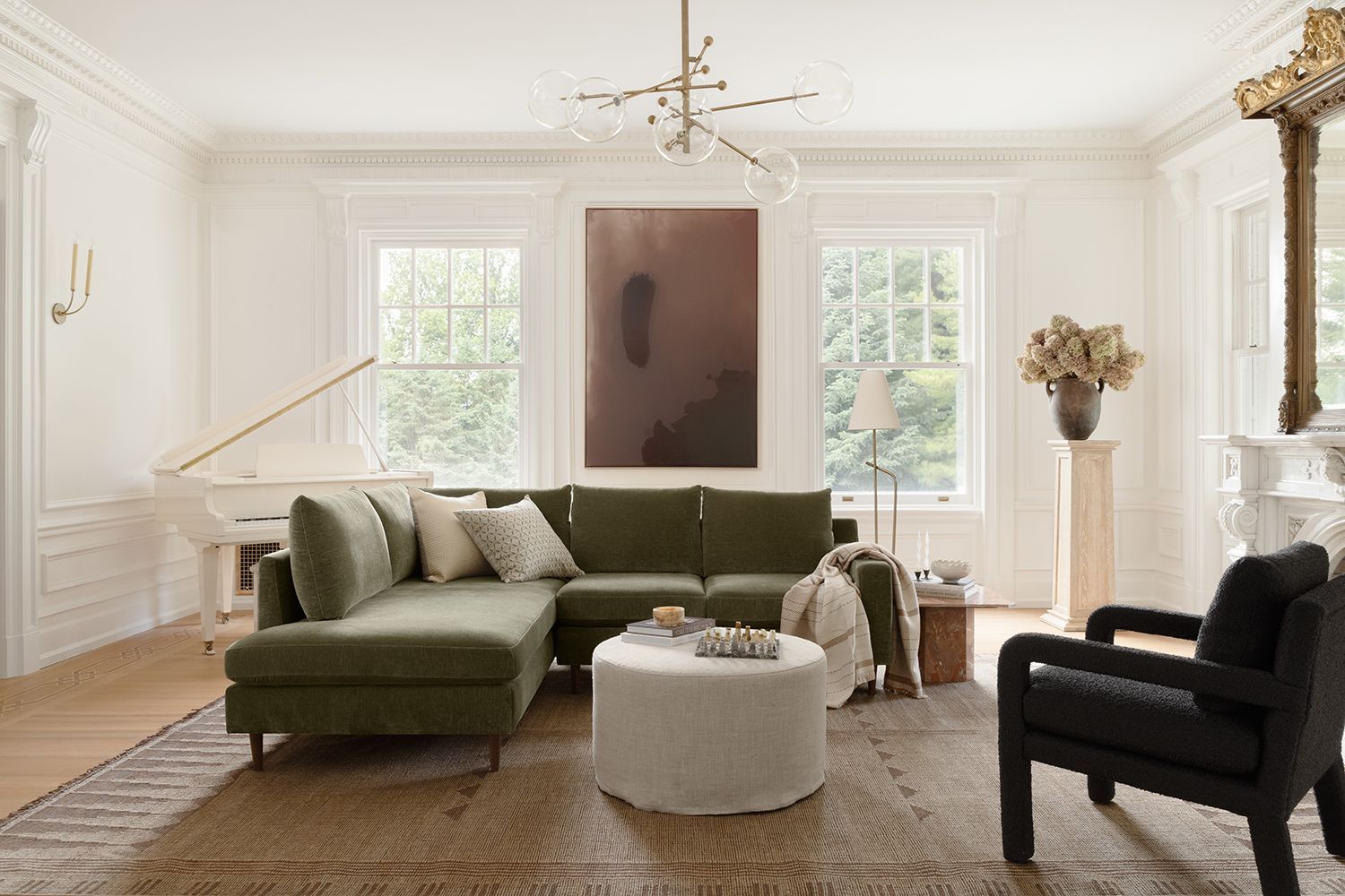 Modern living room with olive green sectional, asymmetrical art placement, and contrasting black accent chair