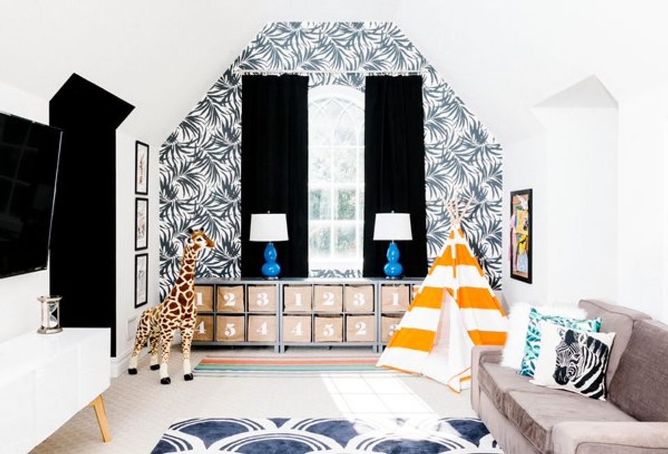 Playroom with botanical wallpaper, black window treatments, natural wood storage, and pops of yellow and blue accents.