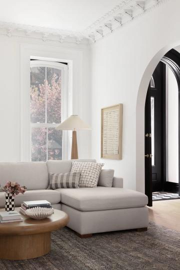 Minimalist cream and gray sitting area with natural wood accents and dramatic black architectural doorway