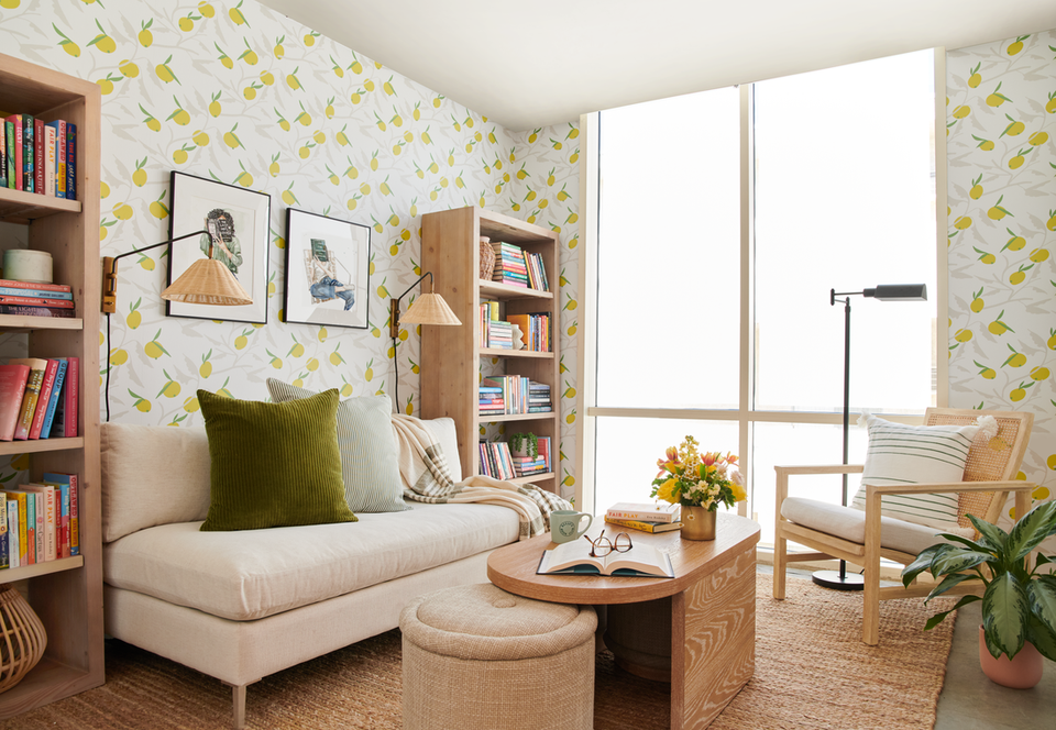 Cozy reading nook with yellow botanical wallpaper, natural wood shelving, and neutral upholstered seating