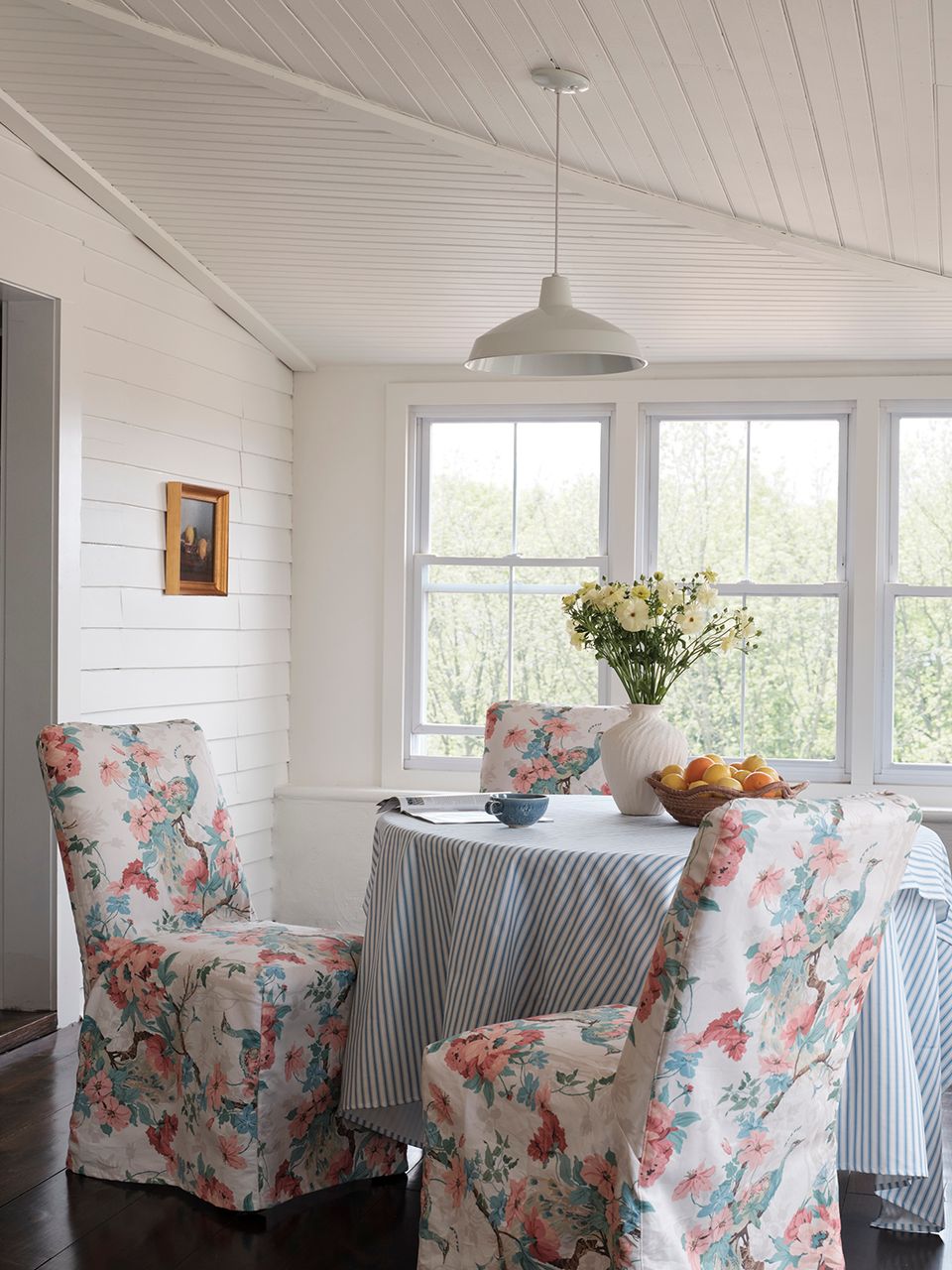 Cottage-style sunroom featuring floral slipcovers, shiplap walls, and farmhouse charm