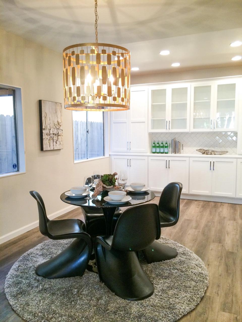 Modern dining area with sculptural black chairs, pendant lighting, and white kitchen cabinetry
