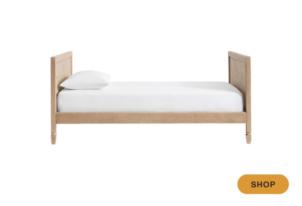 Scandinavian daybed with natural wood frame, white mattress, and rattan panel details.