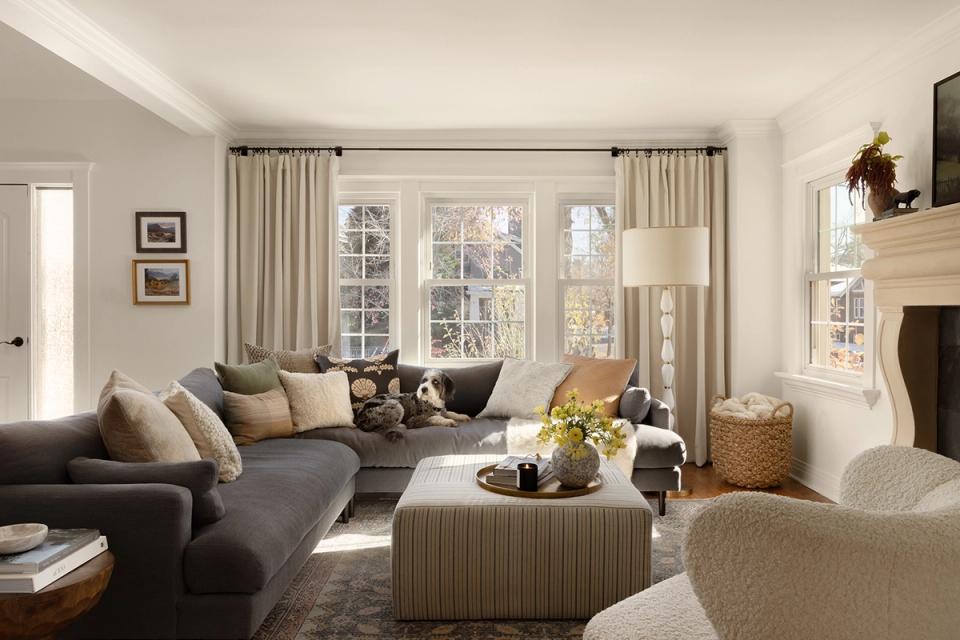 Bright modern living room blending warm neutrals with charcoal sofa, cream accents, and fireplace focal point.