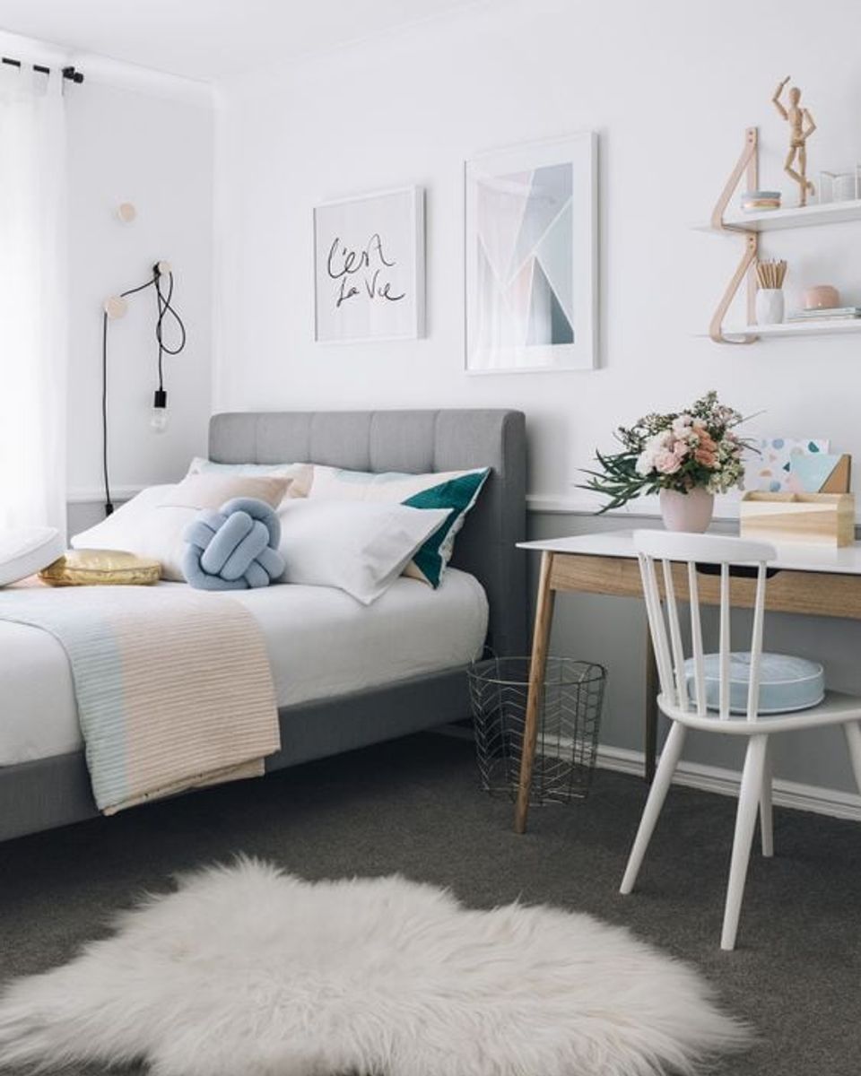 Scandinavian teen bedroom with gray upholstered bed, soft pastels, minimalist line art, and natural wood desk in serene neutral palette