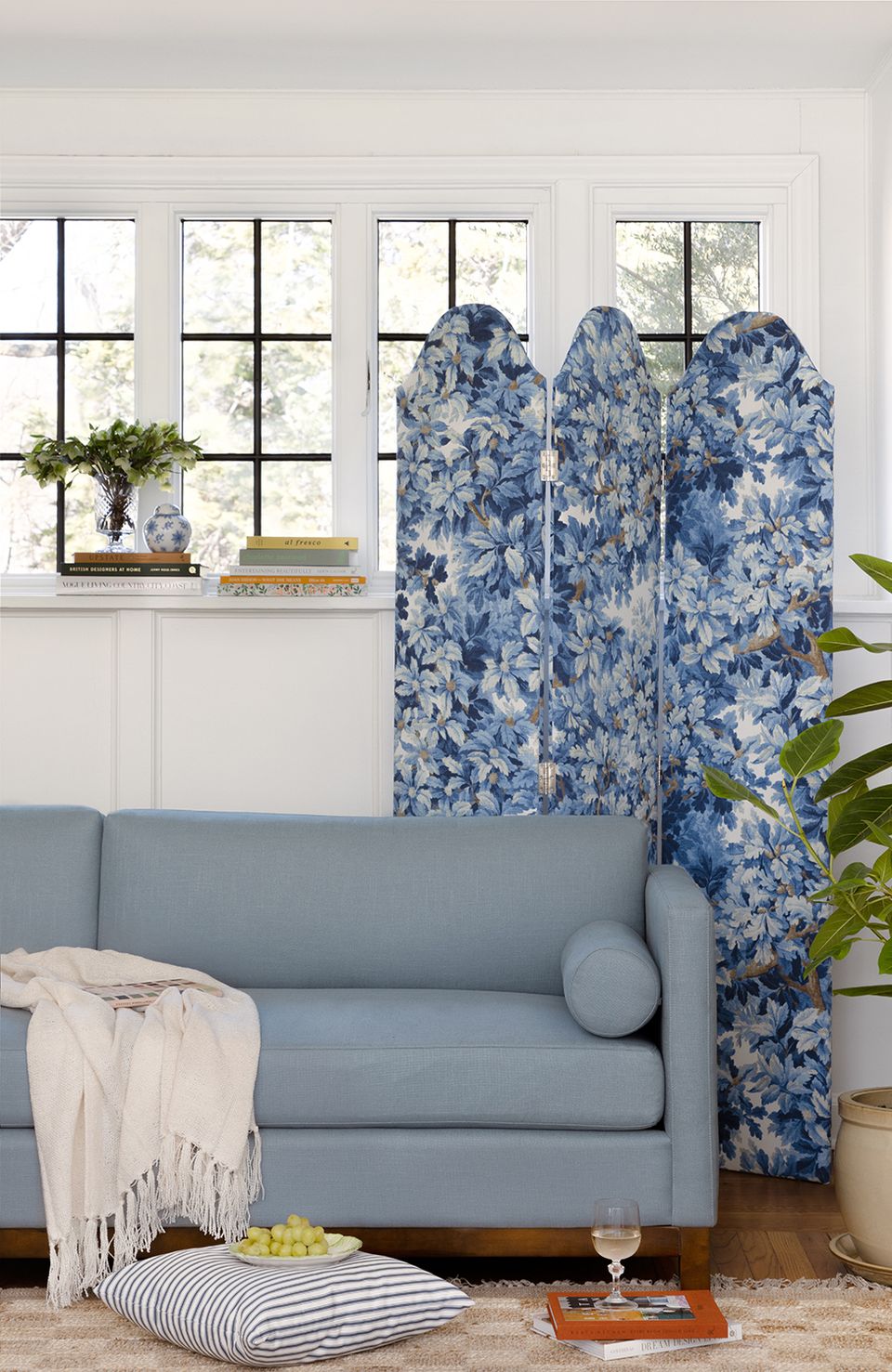 Bright modern space with blue floral room divider, slate sofa, and black grid windows