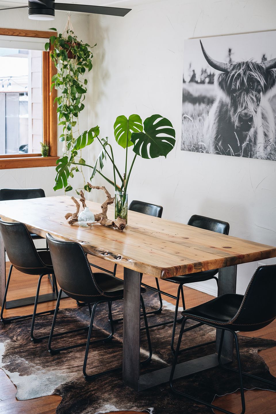 Industrial-rustic dining space with live-edge wood table, black metal chairs, and moody wildlife photography art