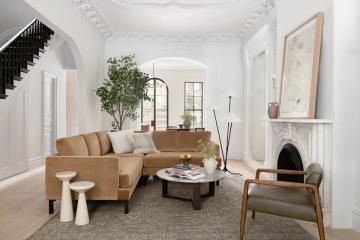 Minimalist modern living room with tan sofa, wooden mid-century accent chair, and serene neutral palette.