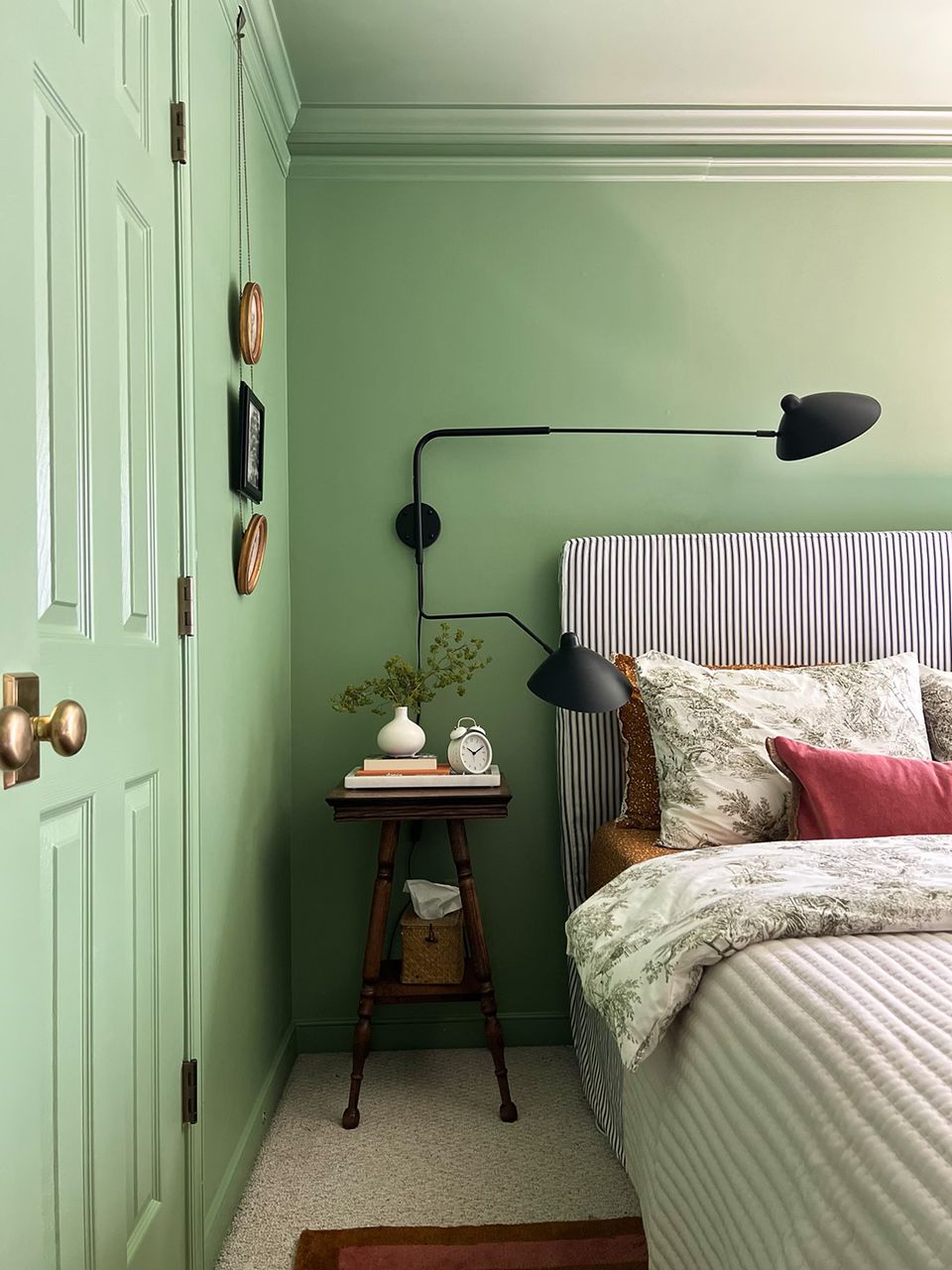 Soft mint-green bedroom with striped headboard and botanical patterned bedding