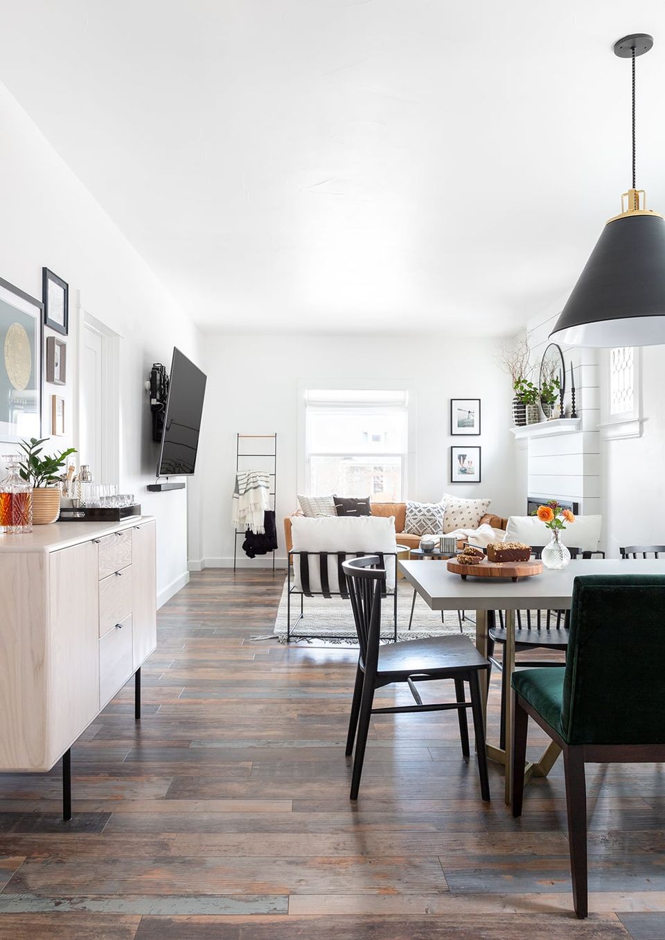 Scandinavian farmhouse dining area with white cabinetry, dark wood table, black pendant light, and airy minimalist aesthetic