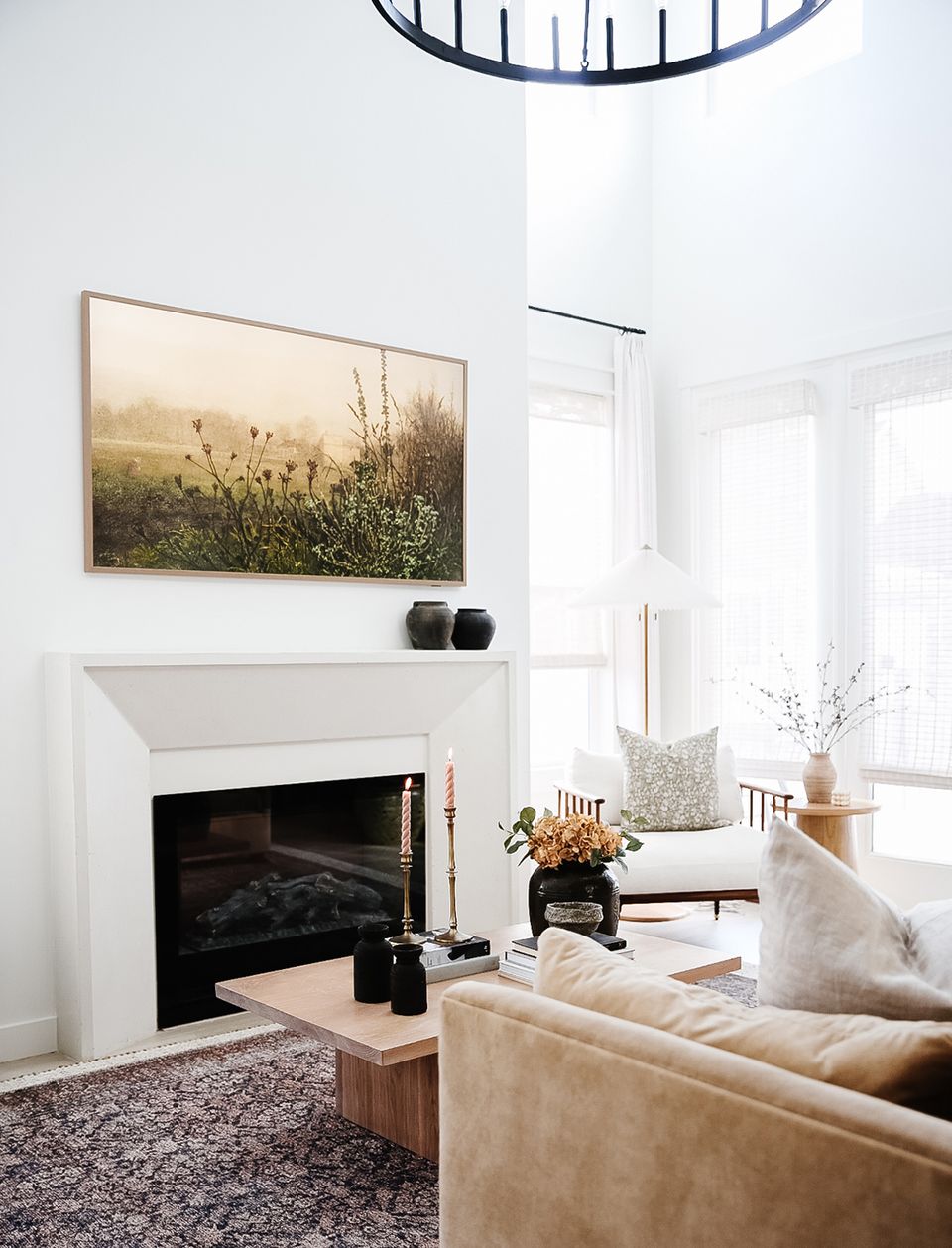 Contemporary minimalist fireplace with neutral tones and landscape artwork above mantel