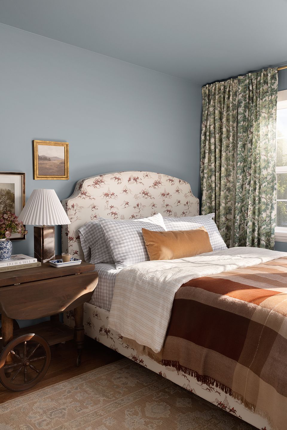 Cozy traditional bedroom with blue walls, floral headboard, and warm wood furnishings