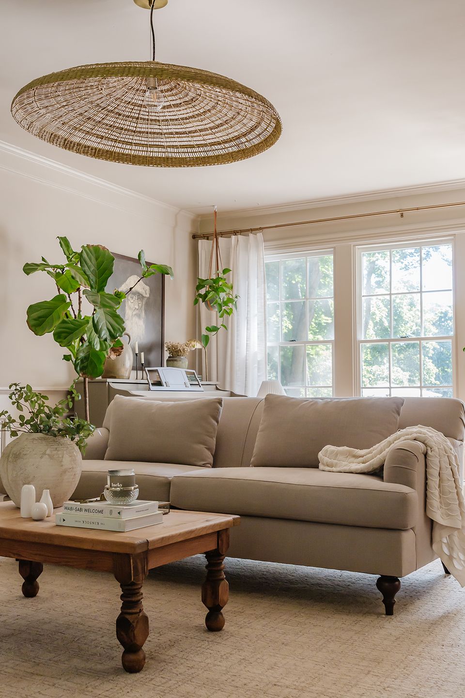 Serene coastal-inspired space with woven pendant light, taupe sofa, and natural greenery