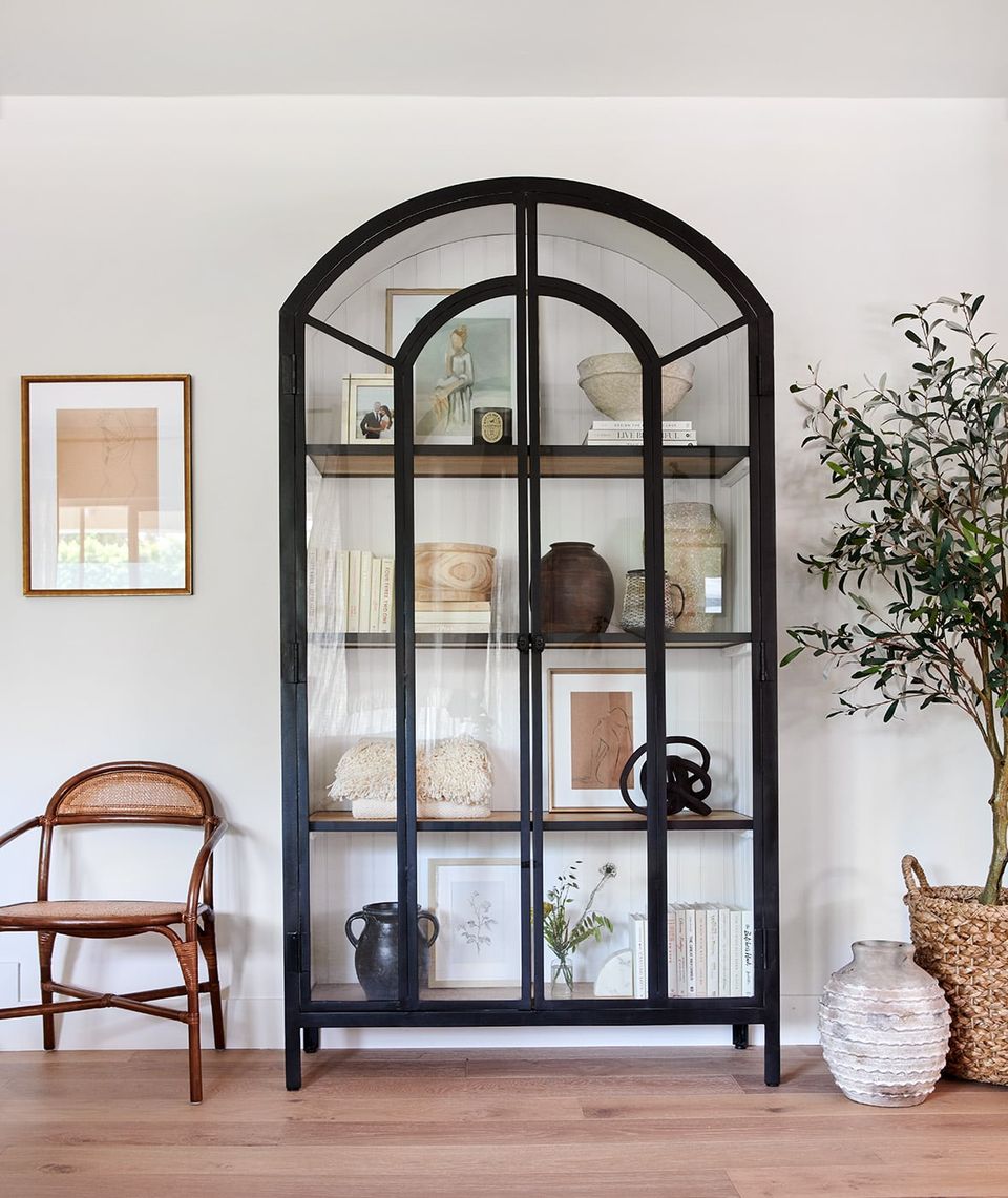 Scandinavian living room with black arched display cabinet, warm wood accents, and minimalist styling
