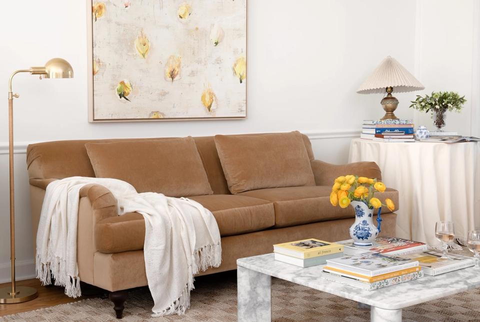 Mid-century modern living space with cognac leather sofa, cream throws, and gold-accented artwork in warm neutral tones