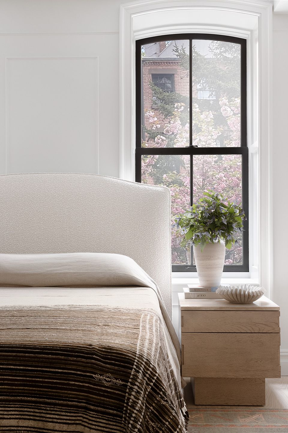 Warm boho bedroom with soft blush pink walls, floral headboard, and natural woven accents