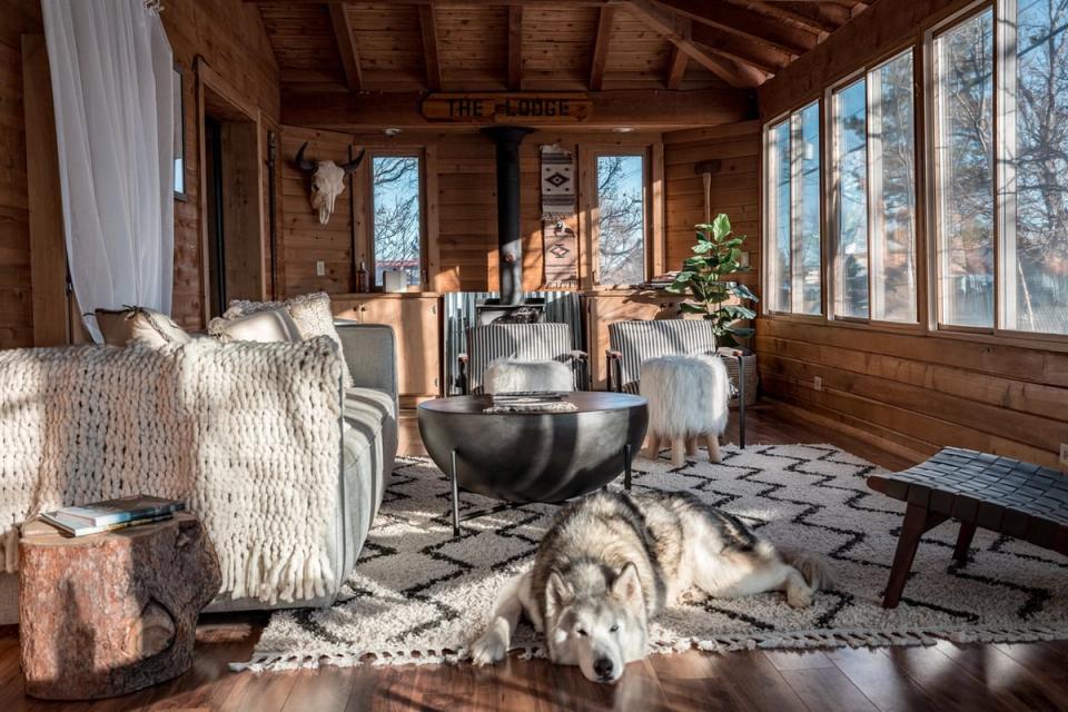 Rustic mountain lodge with warm wood beams, cozy seating, natural textures, and expansive windows framing snowy forest views
