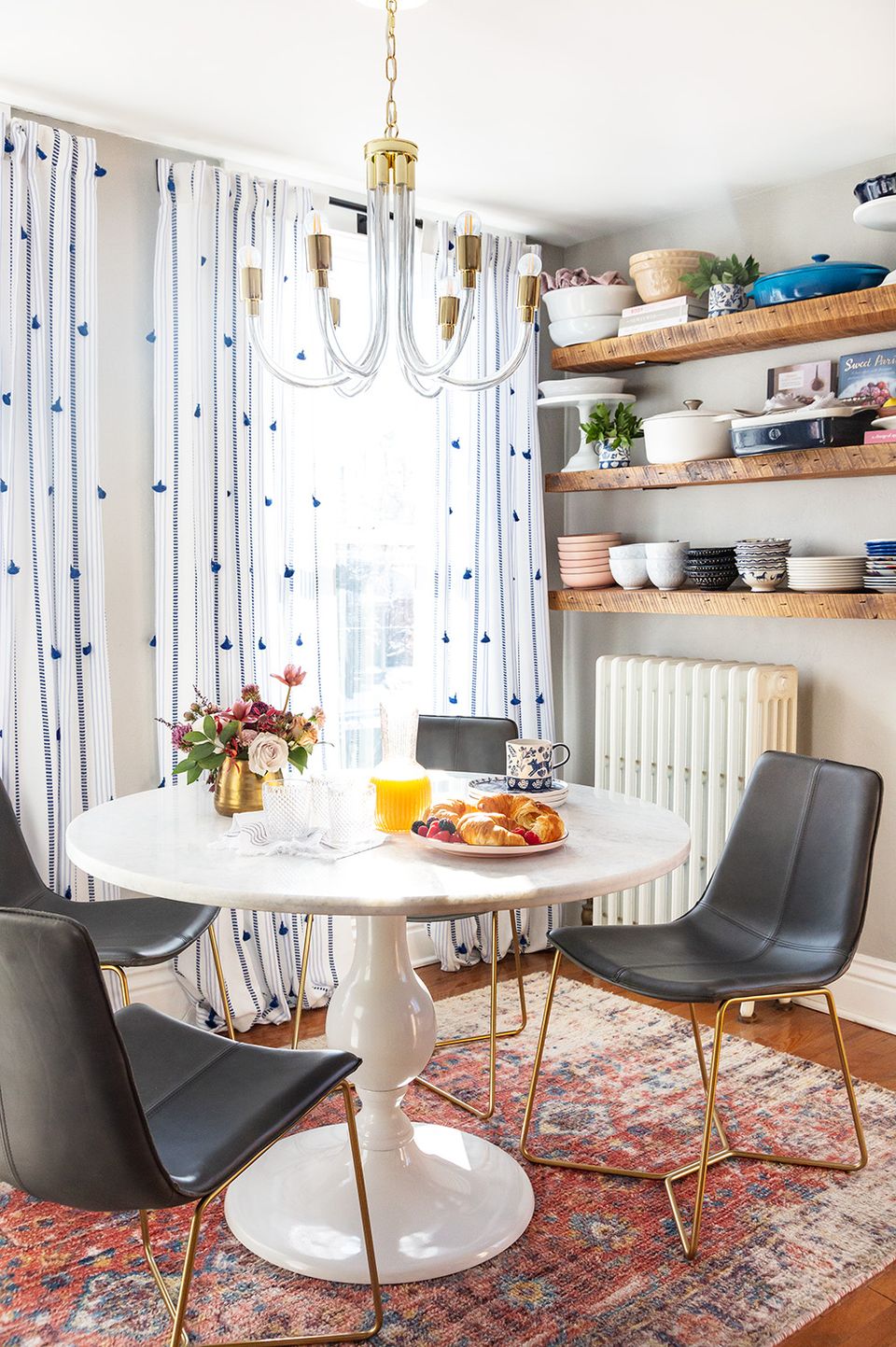 Modern farmhouse dining nook with blue-and-white striped curtains, natural wood shelving, and mid-century seating