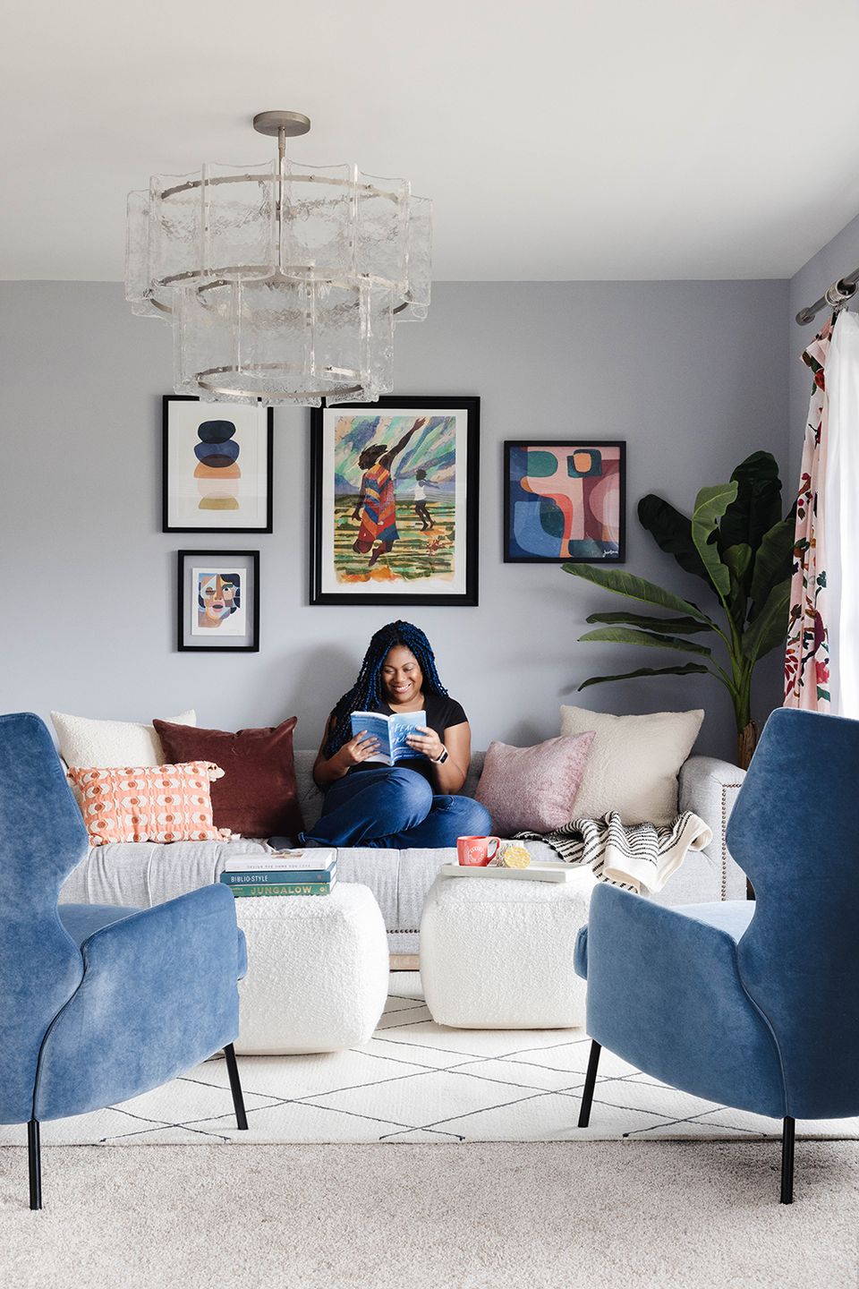 Cozy contemporary reading space with blue armchairs, gallery wall art, and colorful patterned pillows