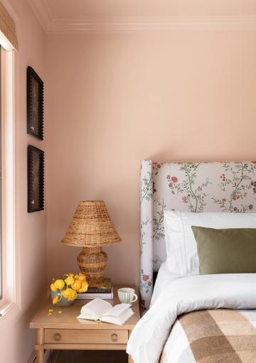 Romantic blush bedroom with floral upholstered headboard, wicker lamp, and warm earthy palette