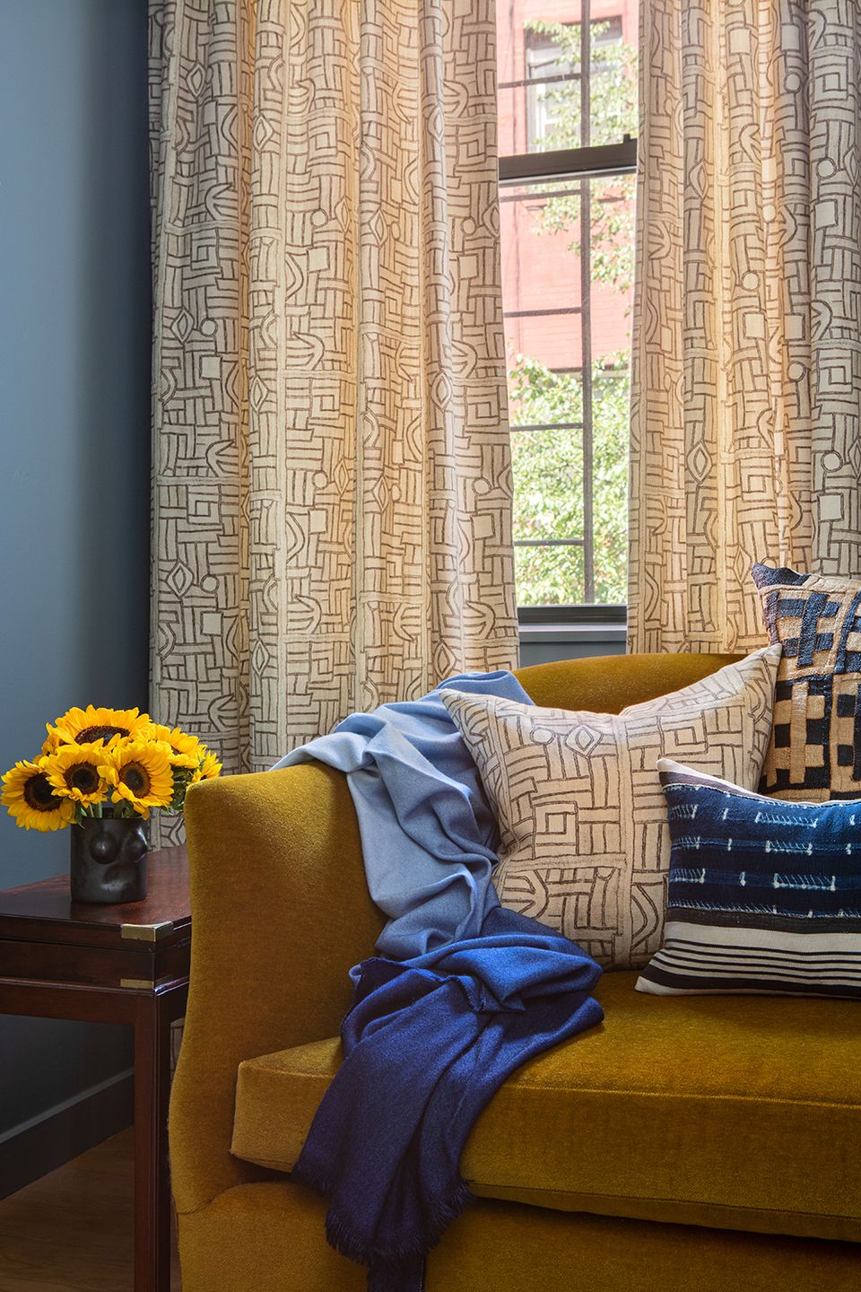 Maximalist living room featuring mustard velvet sofa, geometric patterned curtains, blue accents
