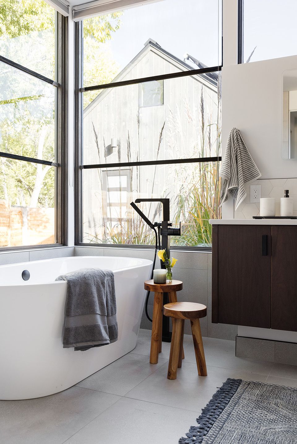 Contemporary spa-inspired bathroom with soaking tub, black industrial towel rack, and garden views