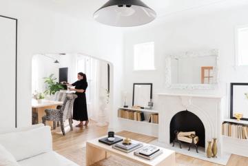 Scandinavian-inspired living room with white walls, natural wood floors, black fireplace, and minimal furnishings creating a bright, airy aesthetic.