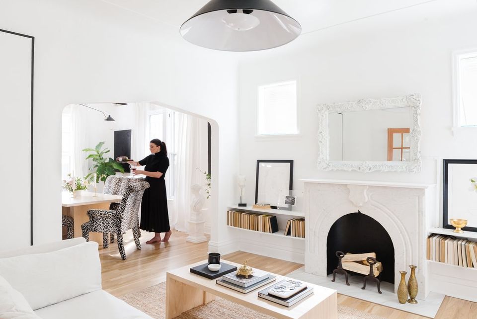 Scandinavian-inspired living room with white walls, natural wood floors, black fireplace, and minimal furnishings creating a bright, airy aesthetic.