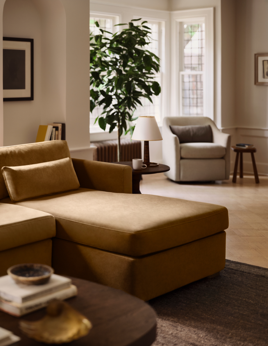 Gold velvet sectional sofa with chaise in a bright, plant-filled living room