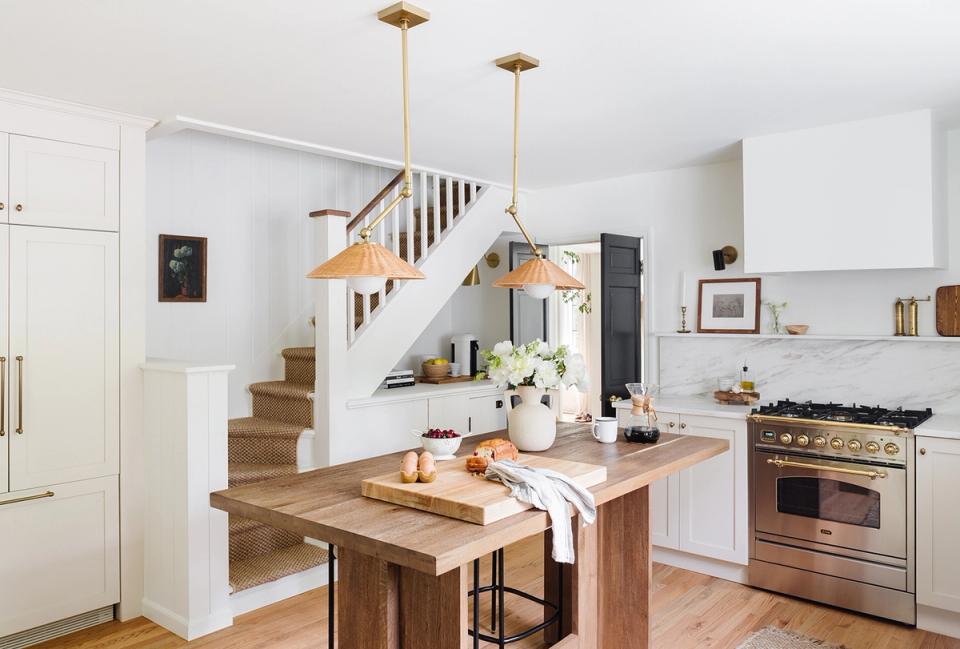 Farmhouse kitchen with natural wood island, brass pendants, and light-filled open concept