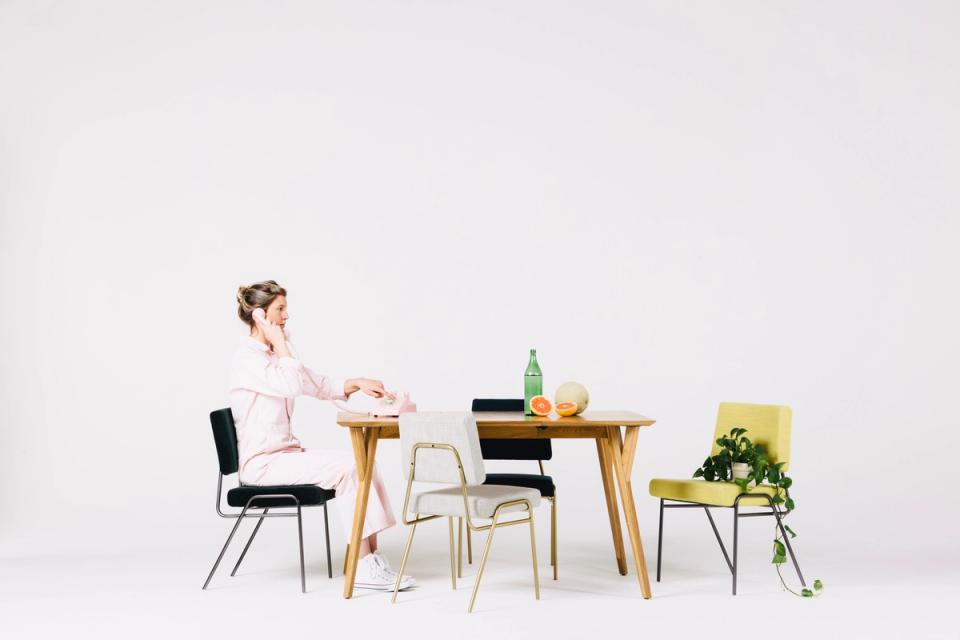 Minimalist Scandinavian dining setup with natural wood table, mixed seating, and bright white backdrop