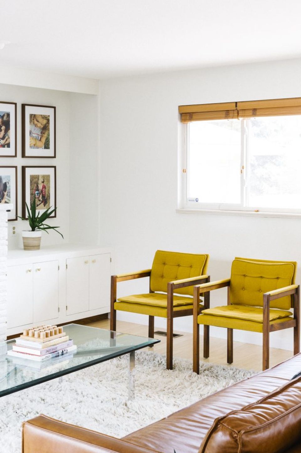 Retro-modern seating area with chartreuse upholstered chairs, wood frames, and curated gallery wall