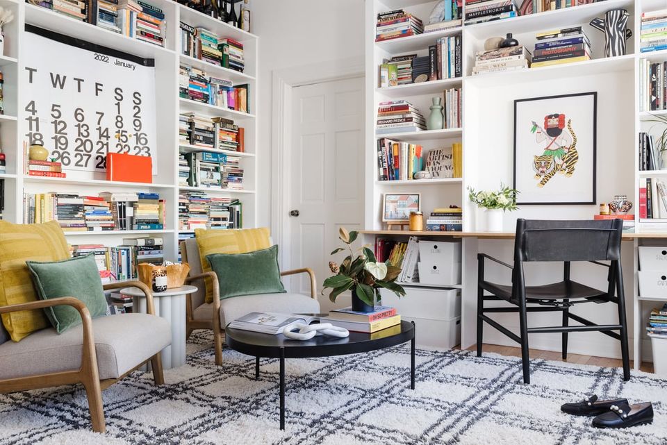 Bright mid-century living room with yellow accent chairs, built-in bookshelves, and geometric patterned rug